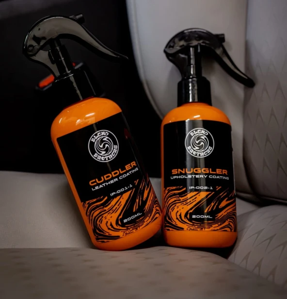 Butelki Snuggler 200 ml(do tkanin) i Cuddler (do skór) na jasnym fotelu samochodowym – ochrona tapicerki.