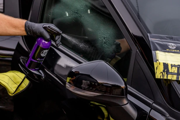 Prezentacja butelki BLOOM Quick Detailer na tle samochodu w profesjonalnym warsztacie