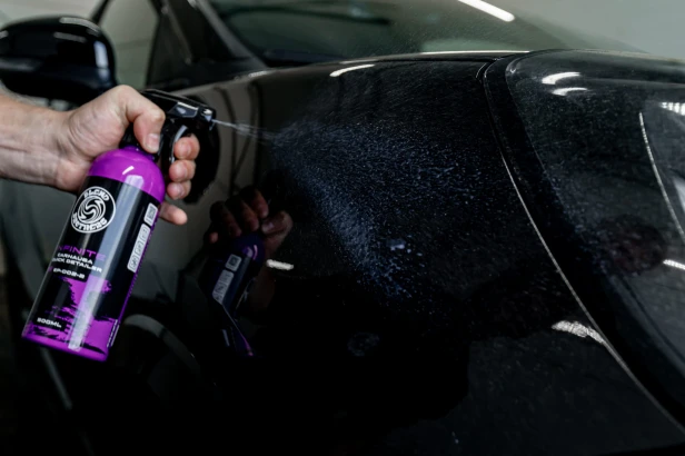 Prezentacja butelki INFINITE Carnauba QD podczas pielęgnacji czarnego lakieru samochodu
