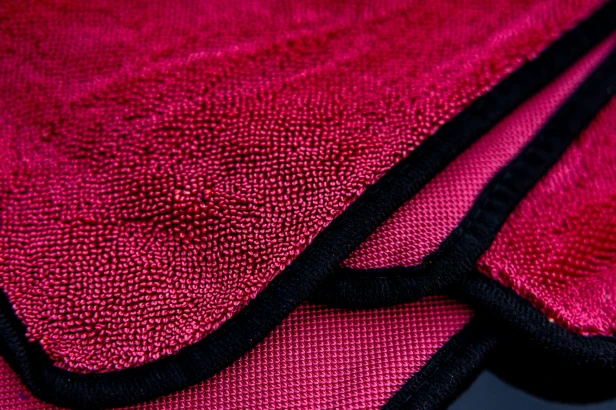 Złożony turkusowy ręcznik Craftie o gramaturze 600GSM z czarnym obszyciem na jasnym tle