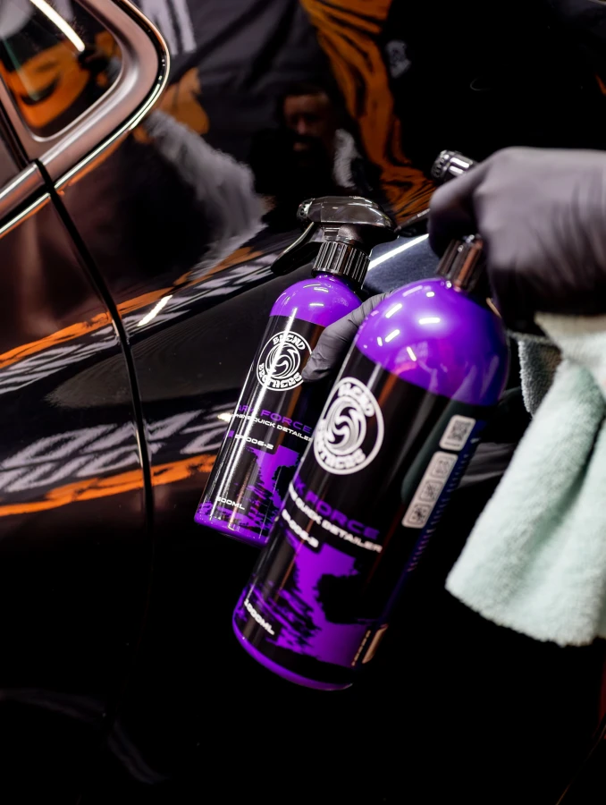 Zbliżenie na butelkę DARK FORCE 500ml trzymaną w dłoni przy boku samochodu.